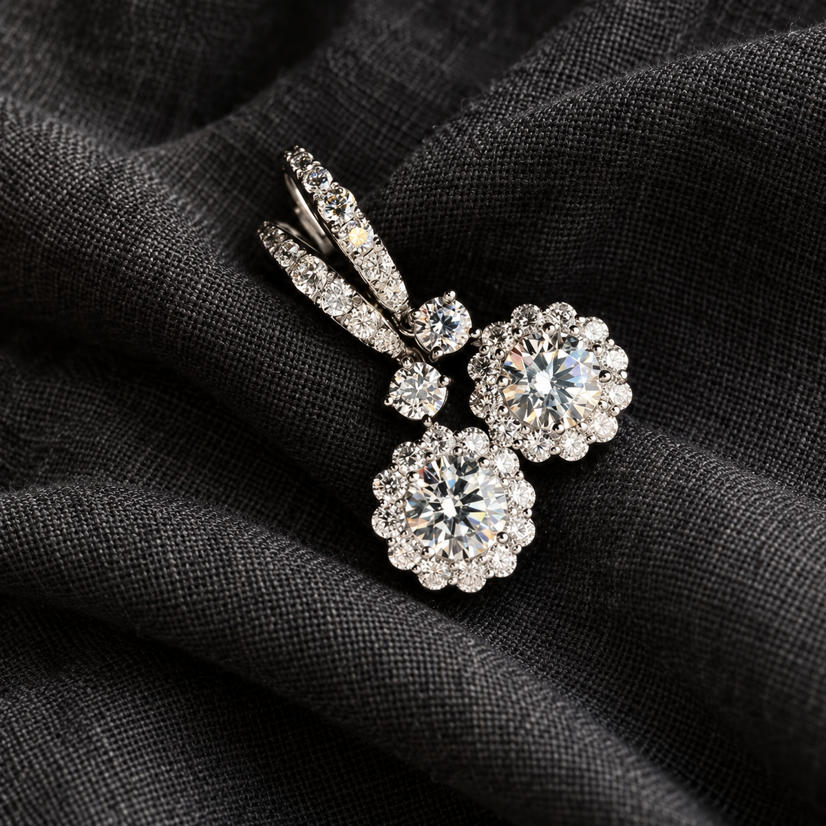 Boucles d’oreilles pendantes fleur en zircone, couleur or blanc, présentées sur un tissu anthracite.
